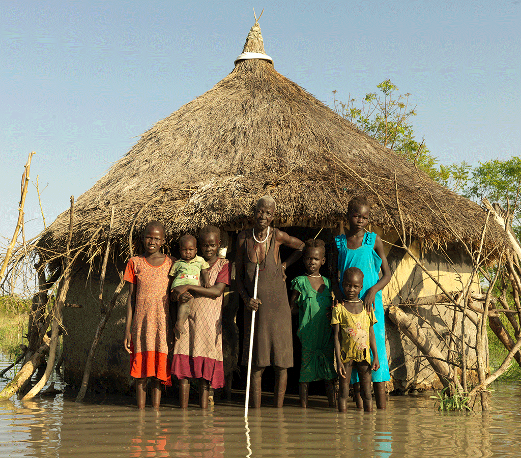 Nyabiele Chan, 80, from Pathiey Village stands by her flooded home with her grandchildren in South Sudan