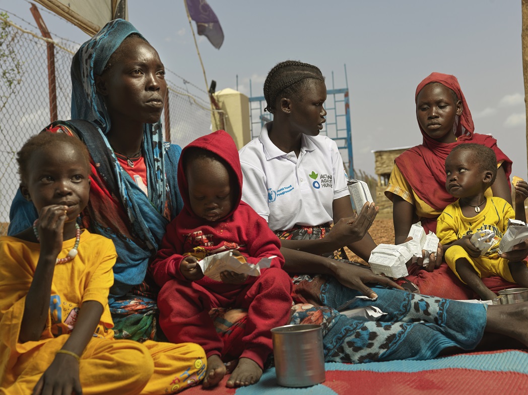 Adheet Akeen Alhia and her child receive energy biscuits from Action Against Hunger worker Mary Anoc Juac