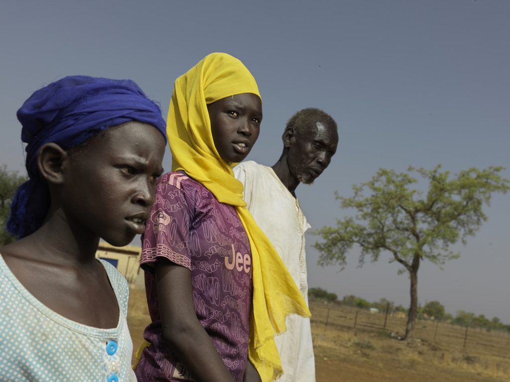 Ackuon, 12-years-old wearing a blue headdress, Arek Luach Nhial, 15-years-old wearing a yellow headdress, and grandfather Kerbino Agany Athien, 60, arrive in South Sudan