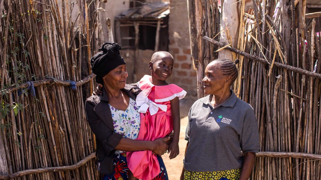 Janet, a community health worker in Tanzania, with a mother and child she's supported to recover from malnutrition.