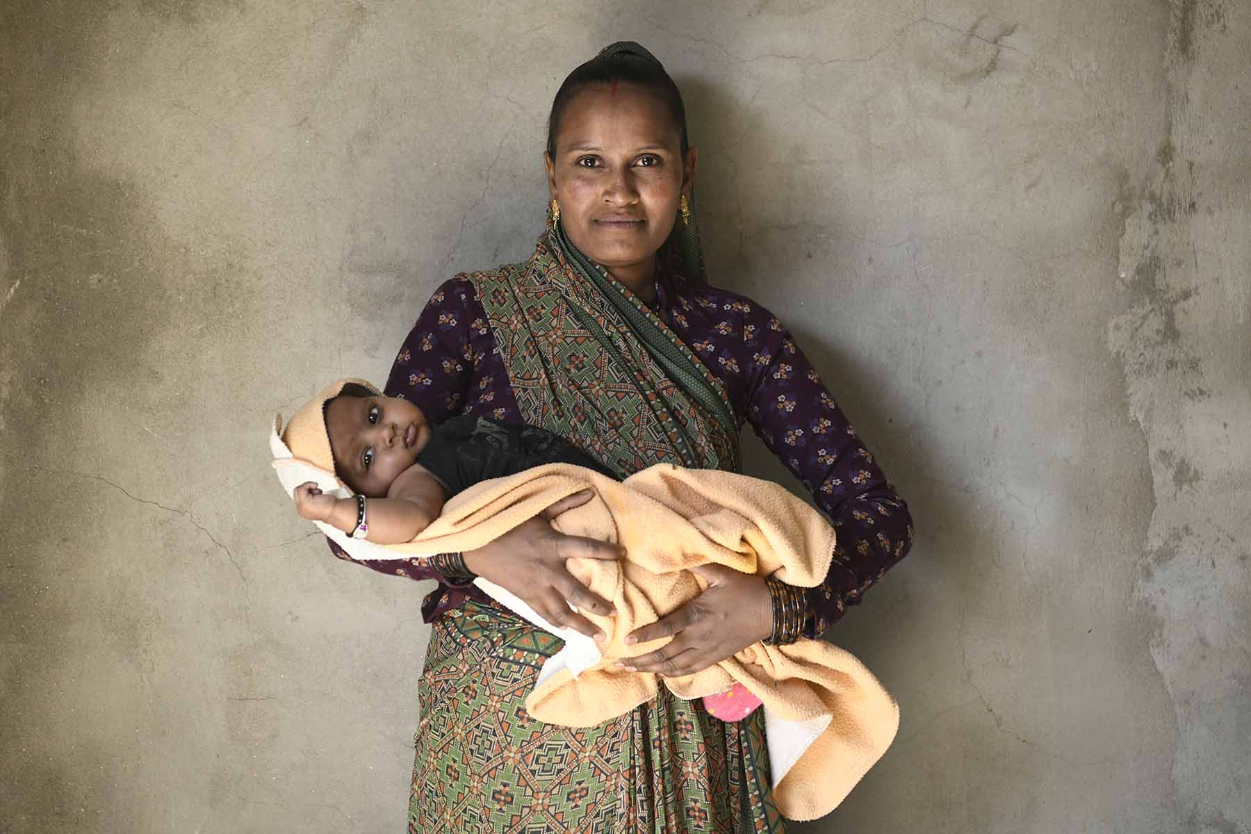 Sonali, a woman from India, looks at the camera while holding her baby Daya.