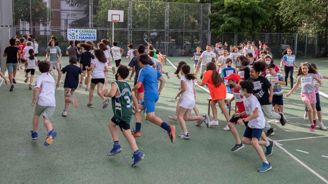 School children running around school sport court in aid of Action Against Hunger.