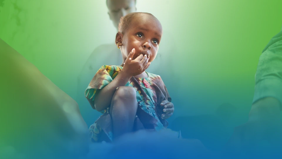 Child in colourful dress sat in front of caregiver.