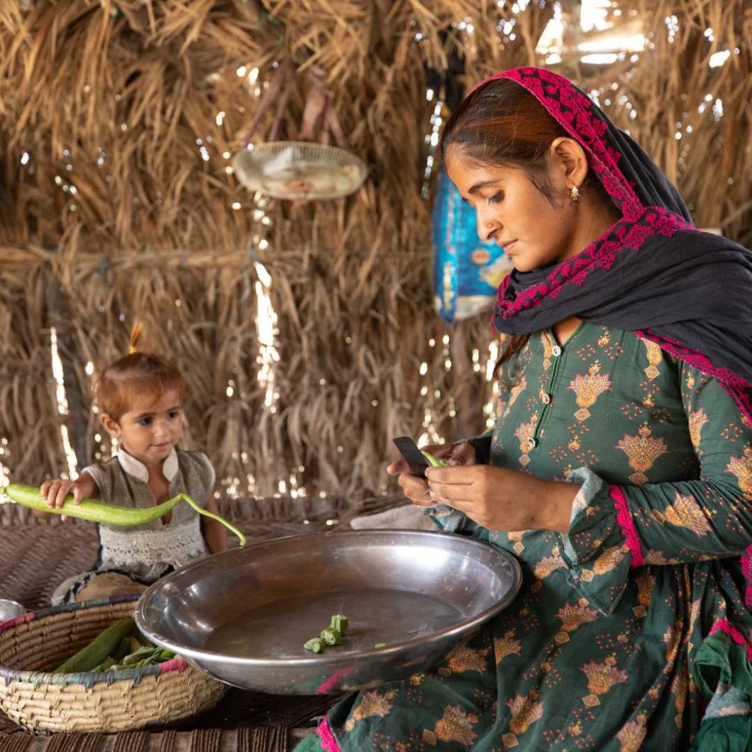 Sumera wearing headscarf preparing vegetables with her daughter in Pakistan.